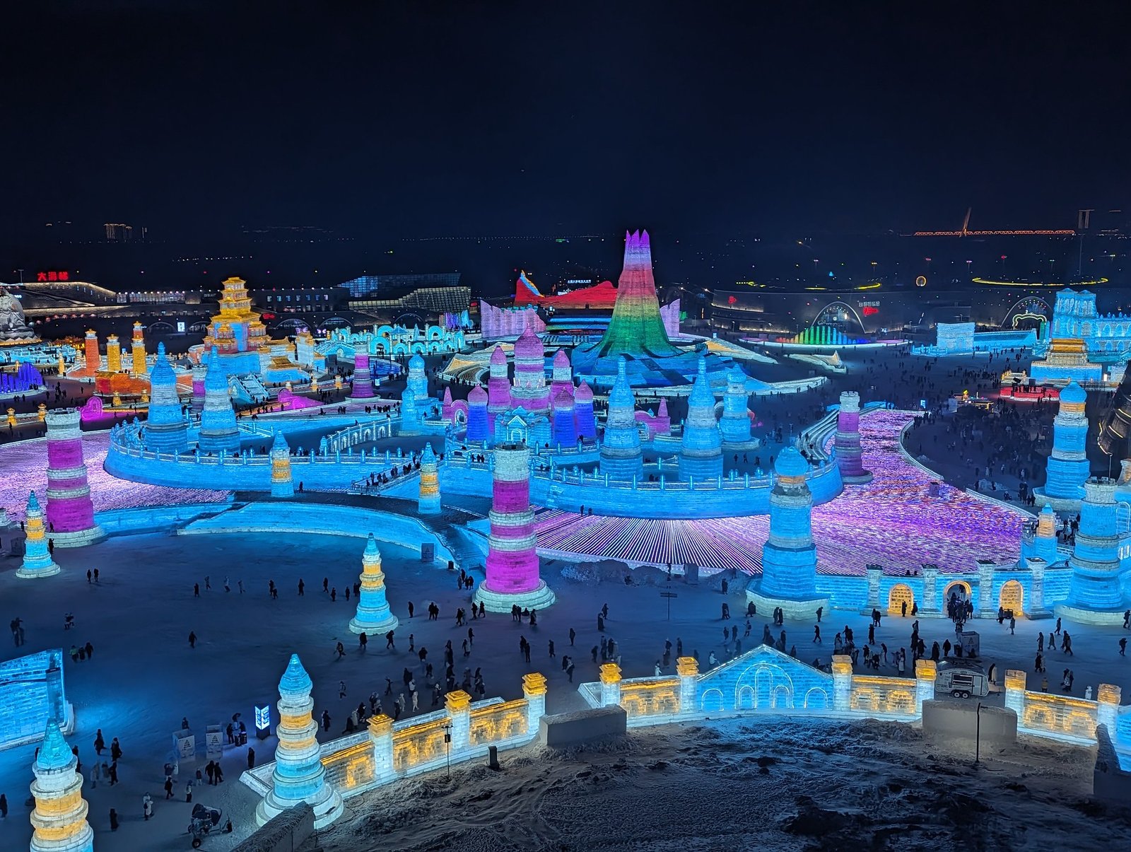 Illuminated ice castle complex at Harbin Ice and Snow Festival, viewed at night