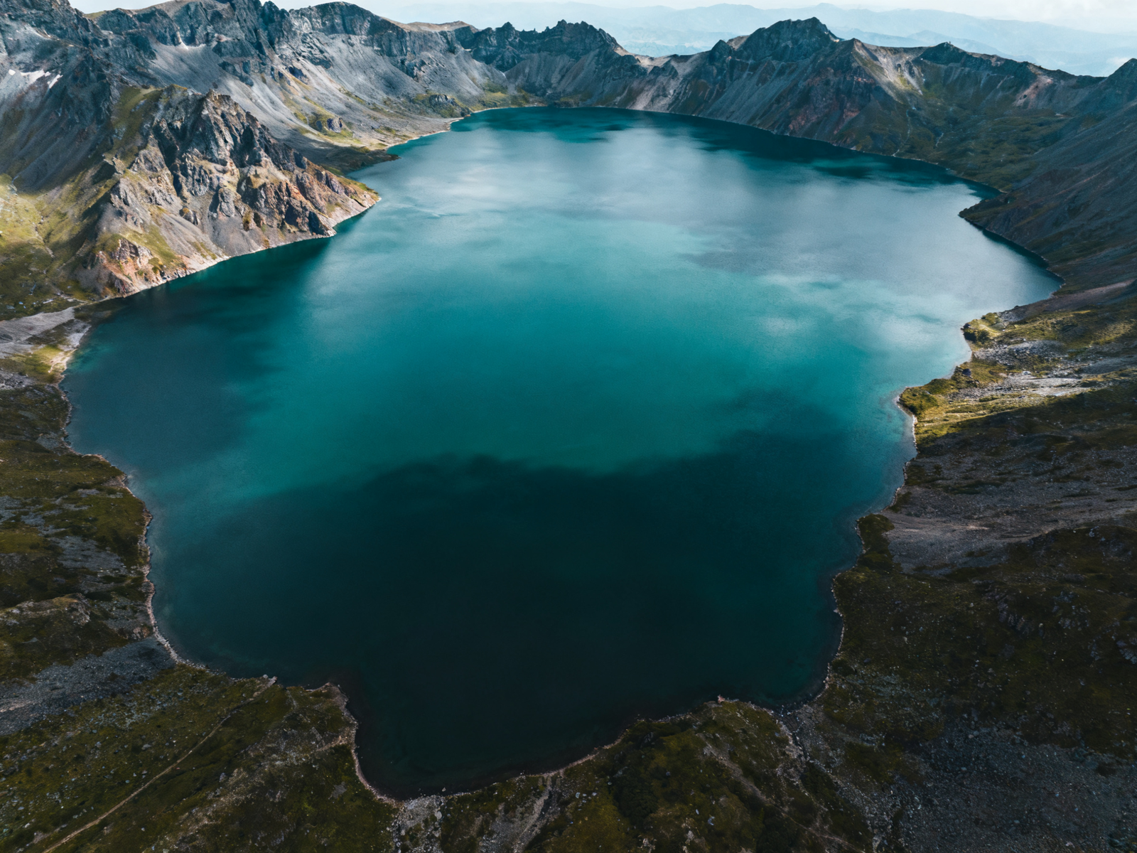 Crater rim of Changbai frames the blue oval of Tianchi; swift weather shifts teach patience.