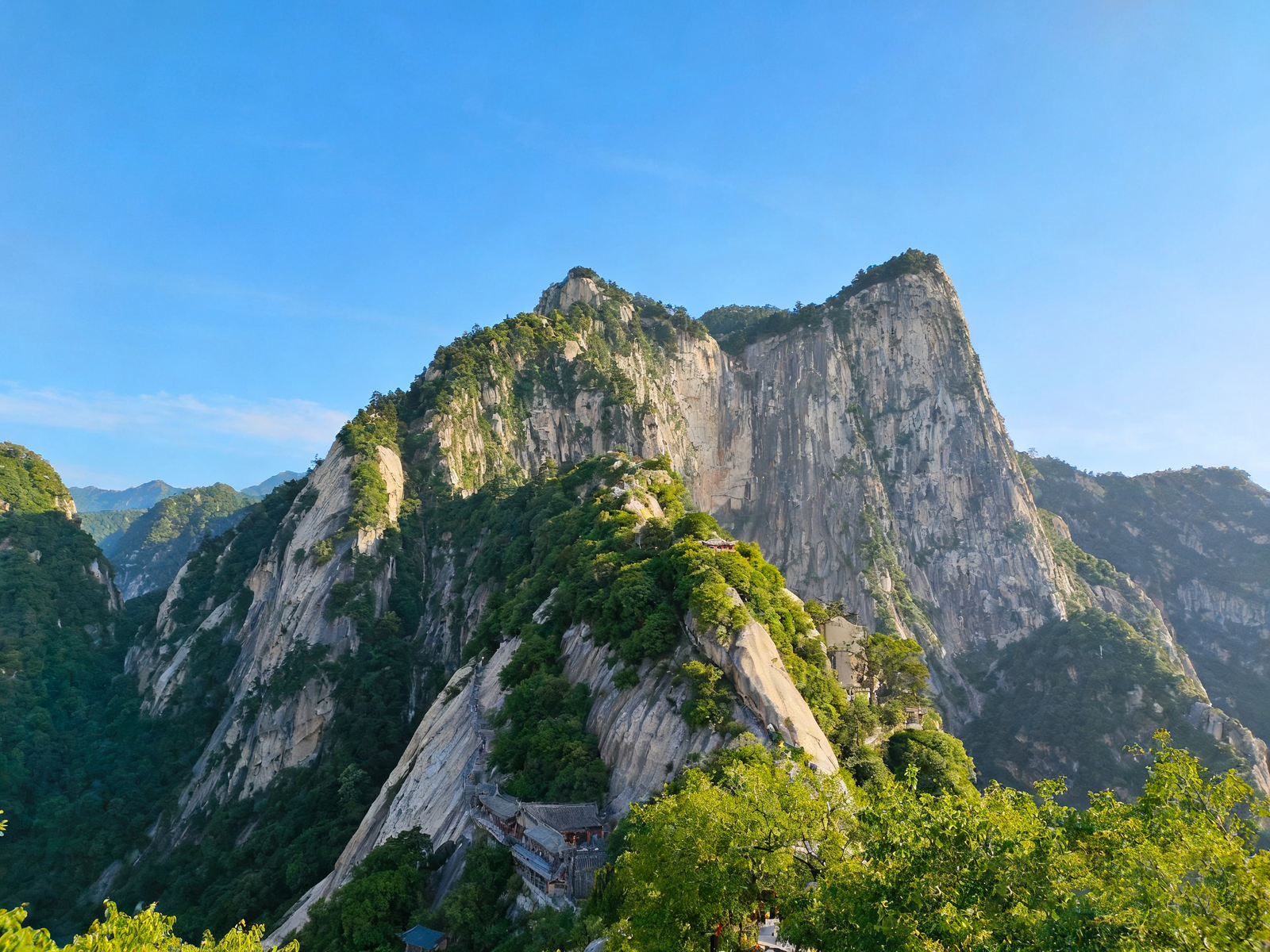 Near-vertical cliffs of Mount Hua with the plank path bolted to the rock, fading into an austere horizon.