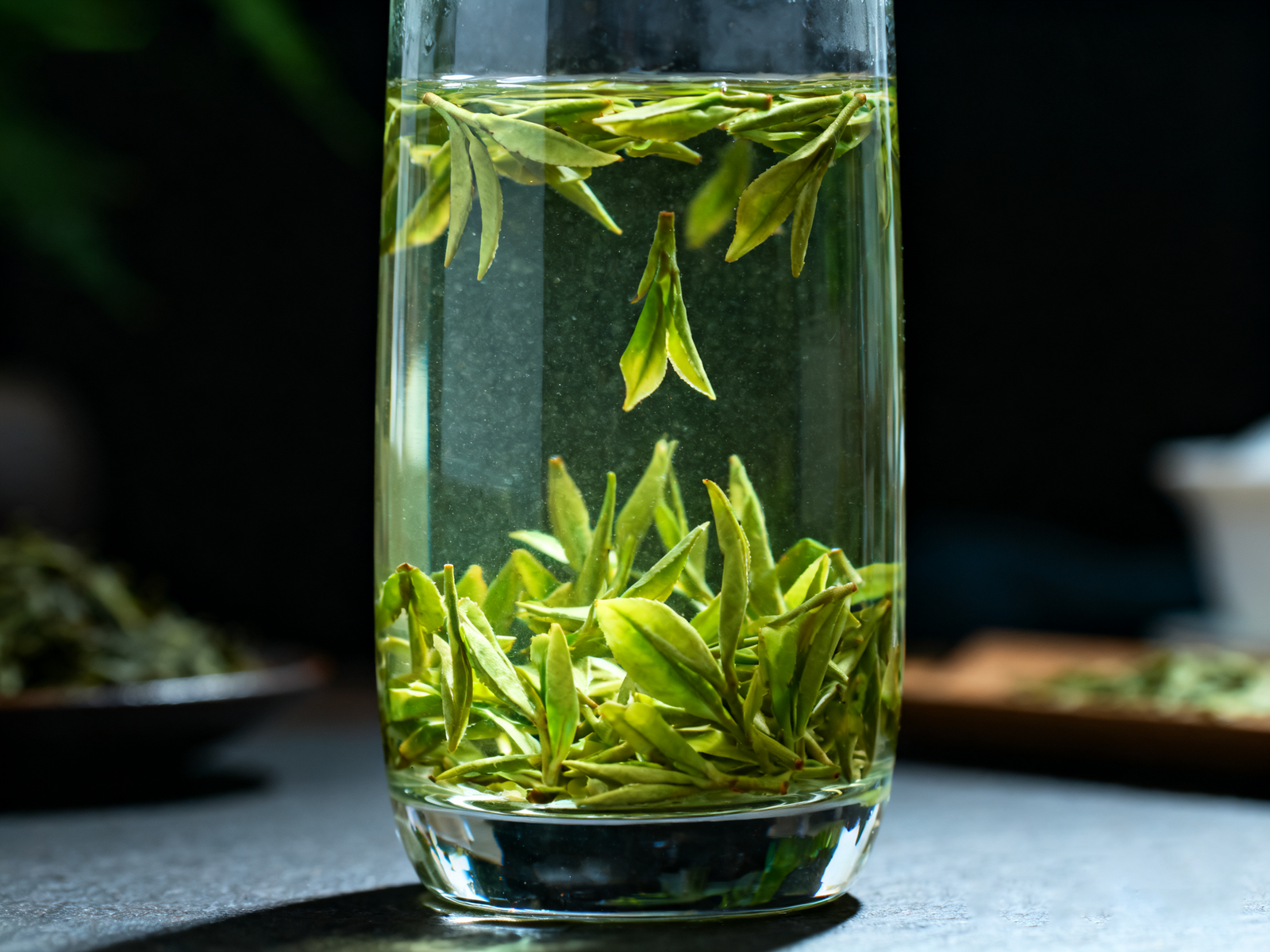 Longjing tea brewing in a tall glass: flat leaves dancing up and down, jade liquor