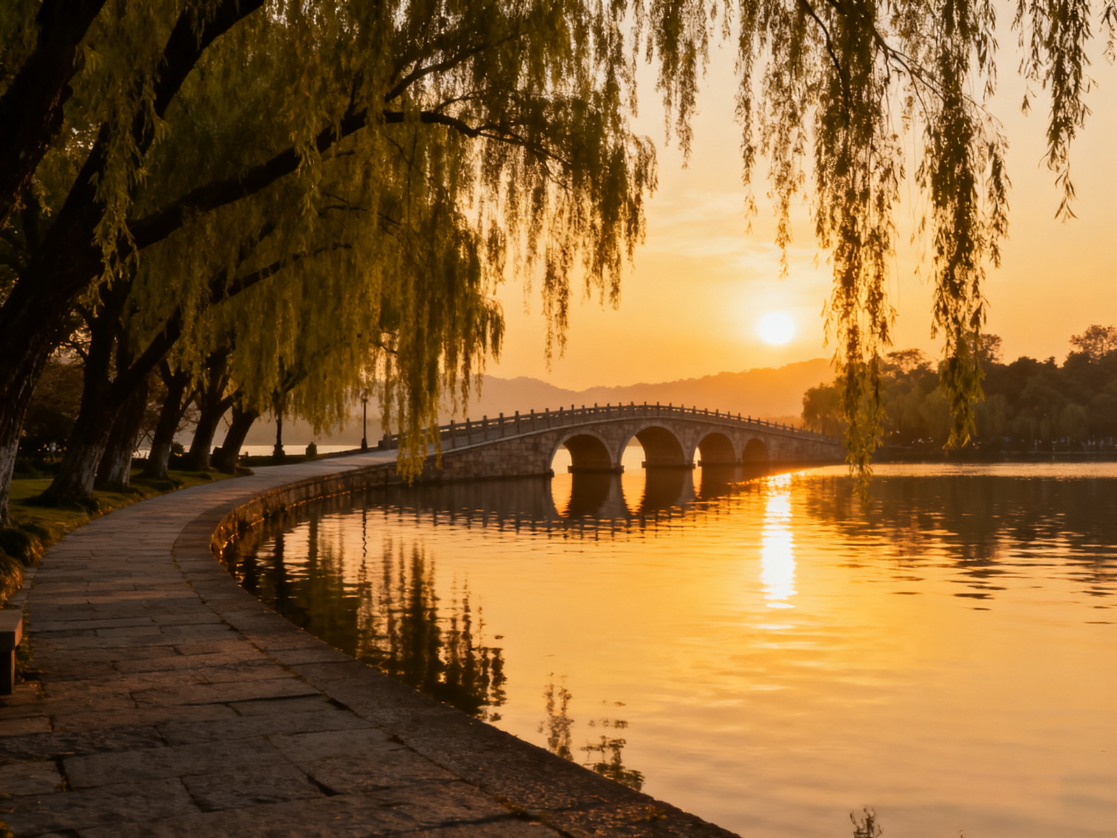 West Lake causeway at sunset: willows and bridges reflecting on calm water