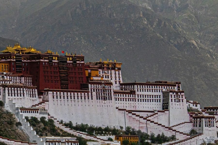 The Potala Palace in Lhasa, Tibet, standing against a backdrop of towering mountains.