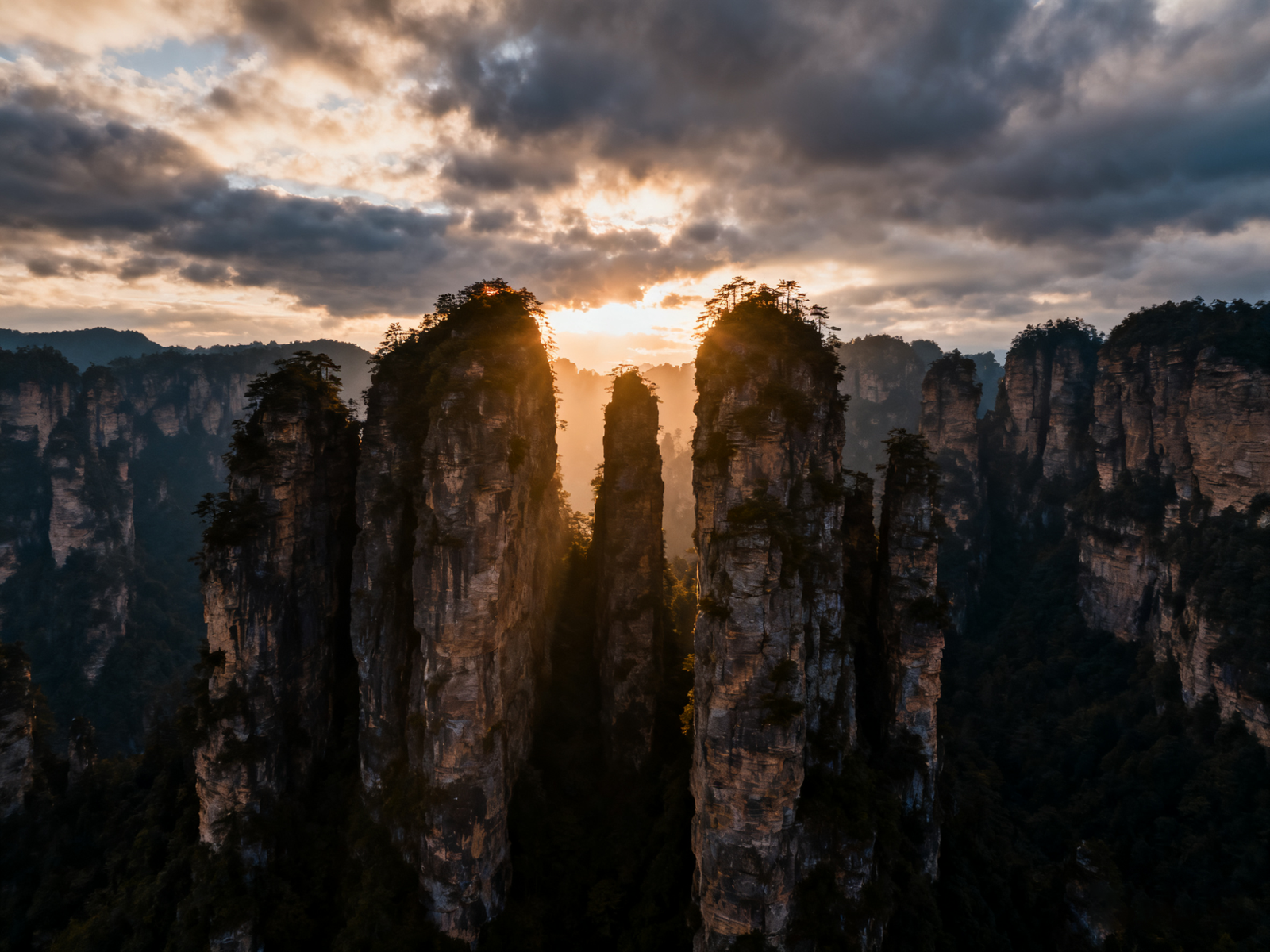 Sandstone pillars at Zhangjiajie rise like a stone forest; a glass skybridge spans between cliffs.